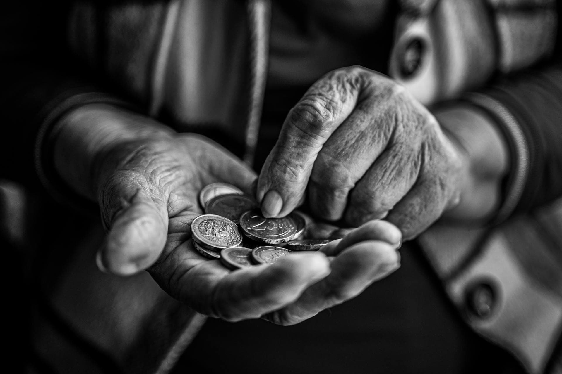 Manos contando monedas sobre un fondo oscuro
